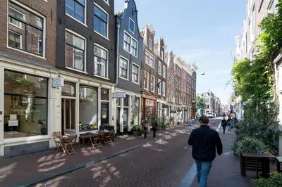 a man walking down a city street with buildings at Herenstraat Residence in Amsterdam