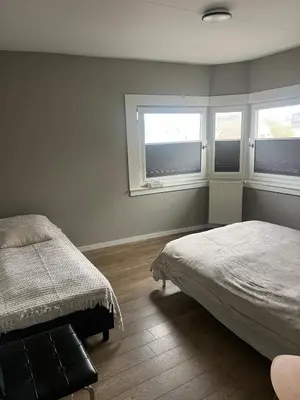 a bedroom with two beds and two windows at Provence Driehuis Apartment in Driehuis