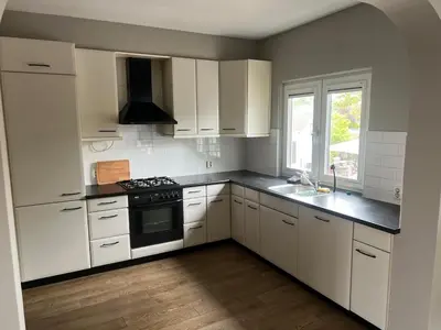 a kitchen with white cabinets and a stove top oven at Provence Driehuis Apartment in Driehuis