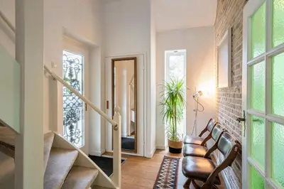 a living room with a staircase and a hallway with chairs at The Green Oasis charming family villa with garden and private parking in Zandvoort