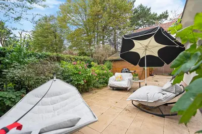 a patio with a chair and an umbrella at The Green Oasis charming family villa with garden and private parking in Zandvoort