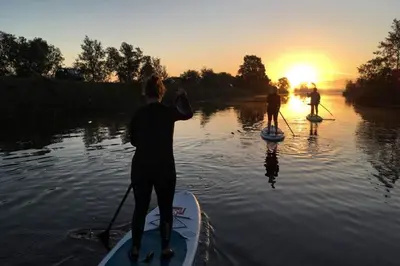 a group of people on paddle boards in the water at Floating holiday home close to AMS