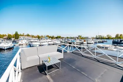 a dock with a couch and a table on a boat at Floating holiday home close to AMS
