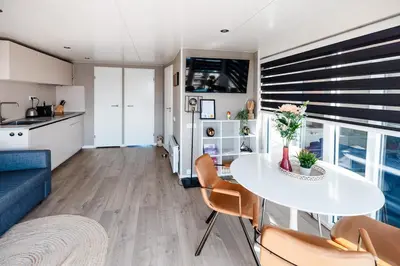 a kitchen and a living room with a table and chairs at Floating holiday home close to AMS