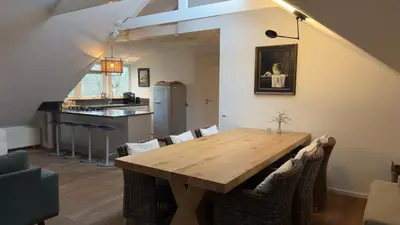 a dining room with a wooden table and chairs at Loft 55 Bergen-Schoorl Luxury Appartement 165m2 in Schoorl