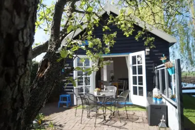 a black and white shed with a table and chairs at Hortensia Eiland in Zegveld
