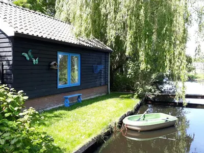a boat sitting in the water next to a house at Hortensia Eiland in Zegveld