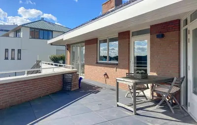a patio with a table and chairs next to a building at Light-flooded villa in Bergen aan Zee