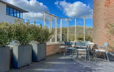 a patio with a table and chairs and a building at Light-flooded villa in Bergen aan Zee