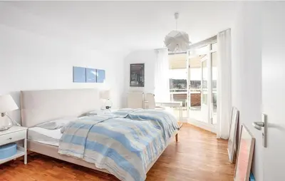 a white bedroom with a bed and a window at Light-flooded villa in Bergen aan Zee