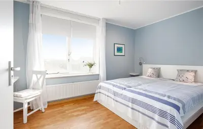 a bedroom with a bed and a window and a chair at Light-flooded villa in Bergen aan Zee