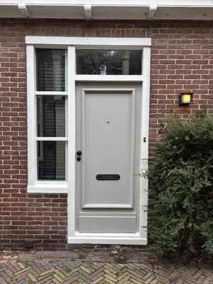 a white door on a brick building with a window at Studio Fnidsen in Alkmaar