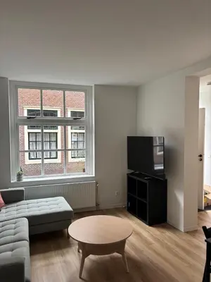 a living room with a couch and a table and a tv at Studio Fnidsen in Alkmaar