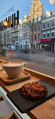 a cup of coffee and a cookie sitting on a table at Spacious Room with private king bathroom in Amsterdam