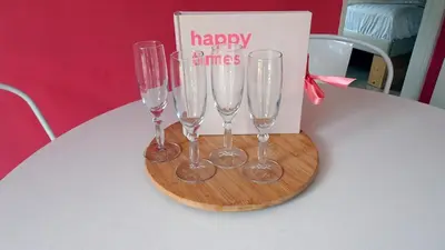 four champagne glasses on a table with a happy times sign at Delightful tropical retreat close to the sea in Warmenhuizen