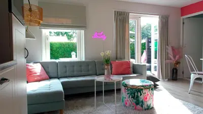 a living room with a couch and a table at Delightful tropical retreat close to the sea in Warmenhuizen