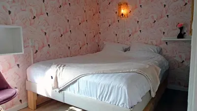 a bedroom with a white bed with pink wallpaper at Delightful tropical retreat close to the sea in Warmenhuizen