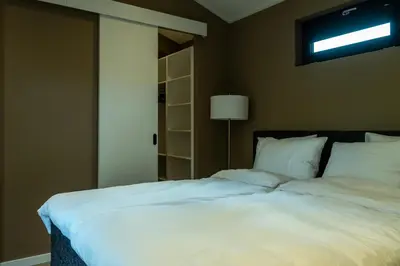 a large white bed in a room with a lamp at Rijn Residentie in Alphen aan den Rijn