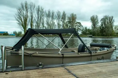 a small boat with a canopy on a dock at Rijn Residentie in Alphen aan den Rijn