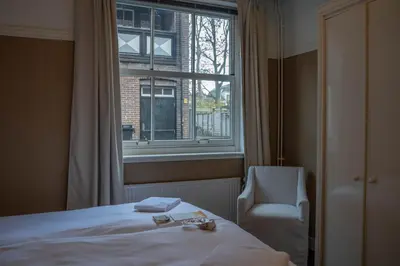 a bedroom with a bed and a chair and a window at The Guesthouse in Gouda