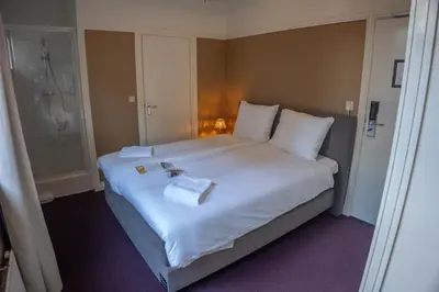 a bedroom with a large white bed with towels on it at The Guesthouse in Gouda