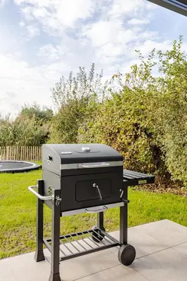 a grill sitting on a table in a yard at Villa Liferla - Wellness met sauna en jacuzzi in Zeewolde