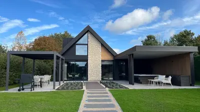 a modern house with a patio and grass at Villa Liferla - Wellness met sauna en jacuzzi in Zeewolde