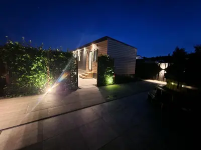 a house with lights on a patio at night at TETchalet met wellness tuin in Berkhout