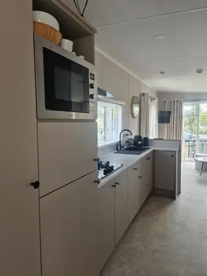 a kitchen with a microwave and a refrigerator with a sink at TETchalet met wellness tuin in Berkhout