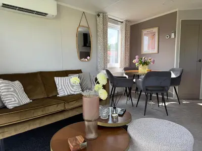 a living room with a couch and a table at TETchalet met wellness tuin in Berkhout