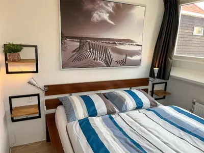 a bedroom with a bed with a picture on the wall at Vakantiehuis Castor 300 m van het strand in Noordwijk aan Zee