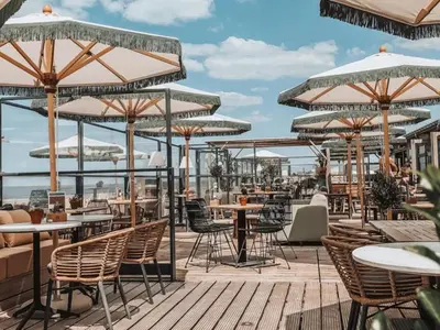 an outdoor patio with tables and chairs and umbrellas at Vakantiehuis Castor 300 m van het strand in Noordwijk aan Zee