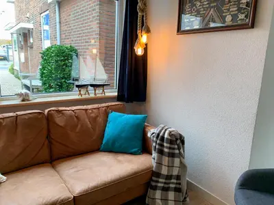 a brown couch sitting in a room with a window at Vakantiehuis Castor 300 m van het strand in Noordwijk aan Zee