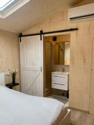 a bedroom with a bed and a bathroom with a sink at Tiny House The Wave in Noordwijk aan Zee