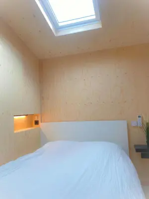 a bedroom with a white bed and a skylight at Tiny House The Wave in Noordwijk aan Zee