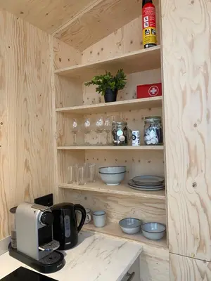 a kitchen with wooden shelves with bowls and plates at Tiny House The Wave in Noordwijk aan Zee