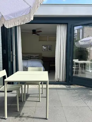 a bedroom with a bed and a table and chairs at The Surf House Noordwijk in Noordwijk aan Zee
