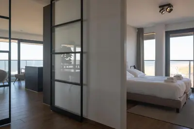 a bedroom with a bed and sliding glass doors at Droomsuites Egmond aan Zee 4 personen by Droomvilla in Egmond aan Zee