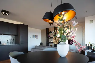 a vase with flowers on a table in a room at Droomsuites Egmond aan Zee 4 personen by Droomvilla in Egmond aan Zee
