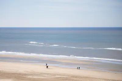 a group of people riding horses on the beach at Droomsuites Egmond aan Zee 4 personen by Droomvilla in Egmond aan Zee