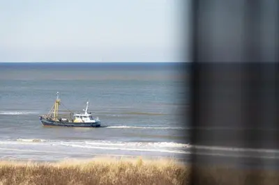 a boat in the water near a beach at Droomsuites Egmond aan Zee 4 personen by Droomvilla in Egmond aan Zee