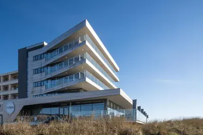 a building with glass windows on the side of it at Droomsuites Egmond aan Zee 4 personen by Droomvilla in Egmond aan Zee