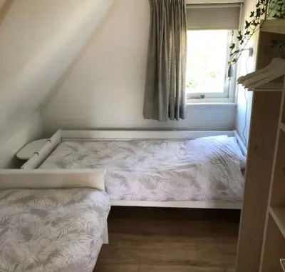 a small bed in a room with a window at De Wielen 23 in Sint Maarten