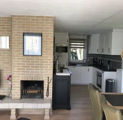 a kitchen and living room with a brick fireplace at De Wielen 23 in Sint Maarten
