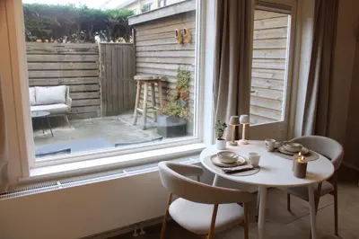 a table and chairs sitting in front of a window at Maison Côte - Moderne Studio met Privé Tuin, Nabij Strand & Circuit in Zandvoort