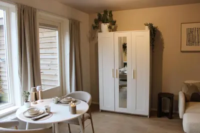 a living room with a table and a white cabinet at Maison Côte - Moderne Studio met Privé Tuin, Nabij Strand & Circuit in Zandvoort