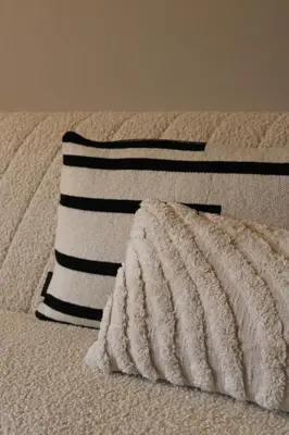 a bed with a black and white blanket and a pillow at Maison Côte - Moderne Studio met Privé Tuin, Nabij Strand & Circuit in Zandvoort