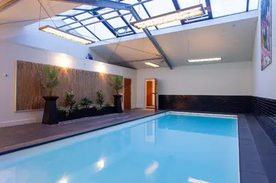 a large swimming pool in a large room with a ceiling at 10P 4B Luxe Villa with Pool and Sauna in Spijkerboor in Spijkerboor