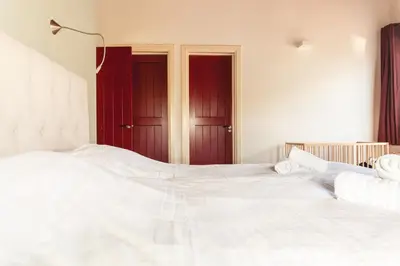 a bedroom with a large white bed with red doors at 10P 4B Luxe Villa with Pool and Sauna in Spijkerboor in Spijkerboor