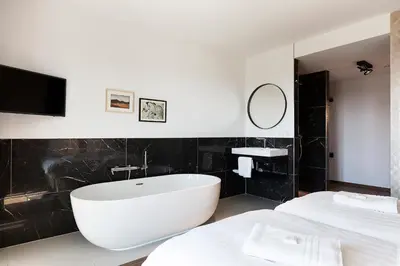 a bathroom with a white tub and a black wall at Droomsuites Egmond aan Zee 8 personen by Droomvilla in Egmond aan Zee